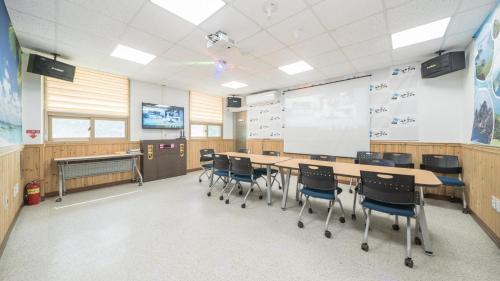 a classroom with a long table and chairs and a whiteboard at Tongyoung Sandeulhae Healling Pension in Tongyeong