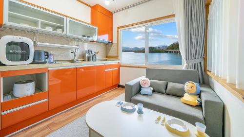 a living room with a couch and a kitchen at Chuncheon El Dorado Kid's Pension in Gapyeong