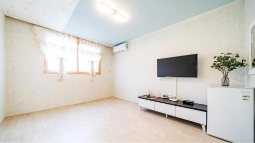 a living room with a tv on the wall at Gangchon Pine Hill Pension in Chuncheon