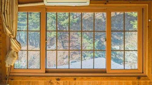 a window in a room with a view of trees at Gapyeong dolgungpensyeon&kaempingjang in Gapyeong