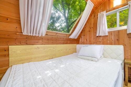 a bed in a wooden room with a window at Gapyeong Karabankaempingnongwon in Gapyeong