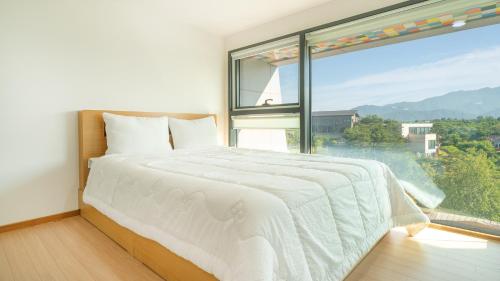 a bedroom with a bed and a large window at goseong theprism pension in Goseong