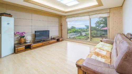 a living room with a couch and a television at jeju oceancliffcottage in Jeju