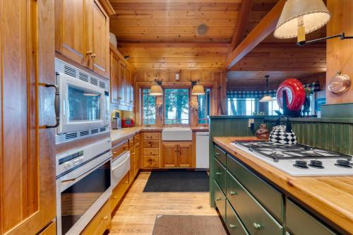 a kitchen with wooden cabinets and a stove top oven at Homewood Lakefront by AvantStay Private Beach Lake Access Views in Homewood