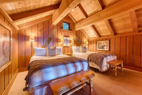 two beds in a room with wooden walls at Homewood Lakefront by AvantStay Private Beach Lake Access Views in Homewood