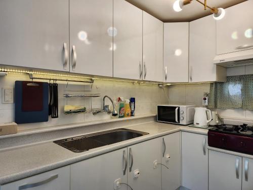 a kitchen with white cabinets and a sink and a microwave at Gyedong byeolchae, Bukchon hanok village & Namsan tower city view Warm morning sunshine Tranquil Rest in Seoul