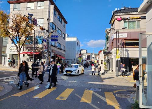 a group of people crossing a busy city street at Gyedong byeolchae, Bukchon hanok village & Namsan tower city view Warm morning sunshine Tranquil Rest in Seoul