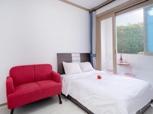 a bedroom with a red chair and a bed at Samcheo Happy House Pension in Samcheok