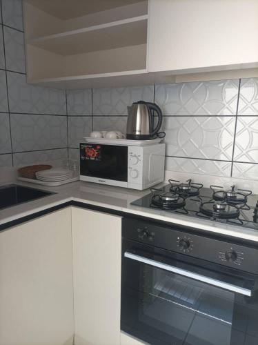 a kitchen with a stove and a microwave at Orient Apartments - Taqah in Sumhuran