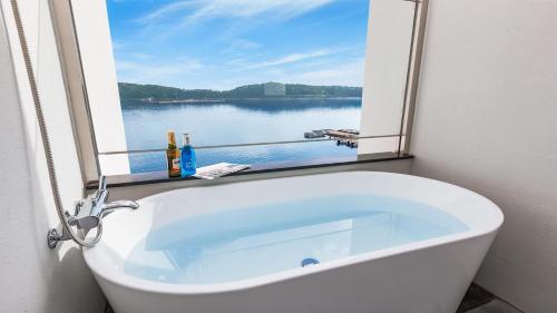a bath tub with a window with a view of a lake at Tongyeong FH365 Pension in Tongyeong