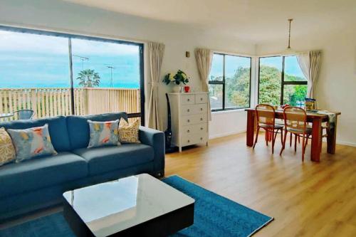 a living room with a blue couch and a table at Seaview house in Howick Auckland in Auckland