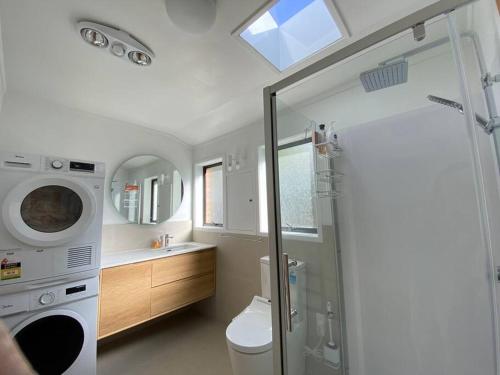 a bathroom with a shower and a washing machine at Seaview house in Howick Auckland in Auckland