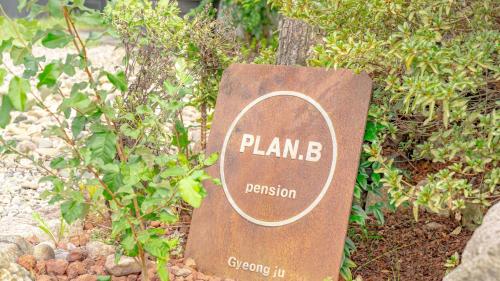 a sign that says plan b protection sitting next to a bush at gyeongju planb pet pension in Gyeongju