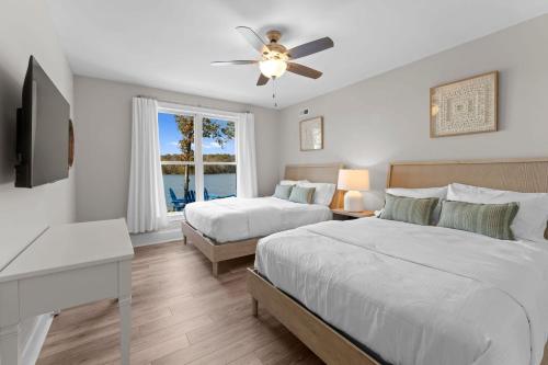 a bedroom with two beds and a ceiling fan at Sunset Pointe by AvantStay Waterfront Beach Fire Pit Sleeps 14 5BDR 4BA in Terrell