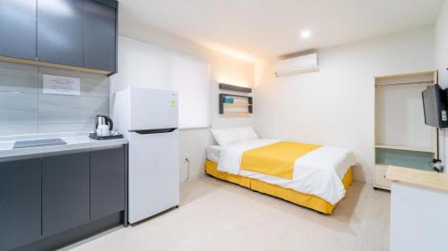 a small kitchen with a bed and a refrigerator at Jeju moons stay in Jeju