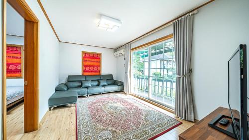 a living room with a couch and a large window at Gapyeong ojeupension in Gapyeong