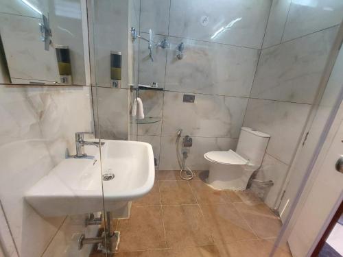 a bathroom with a sink and a shower and a toilet at Hotel Yathin in Mysore