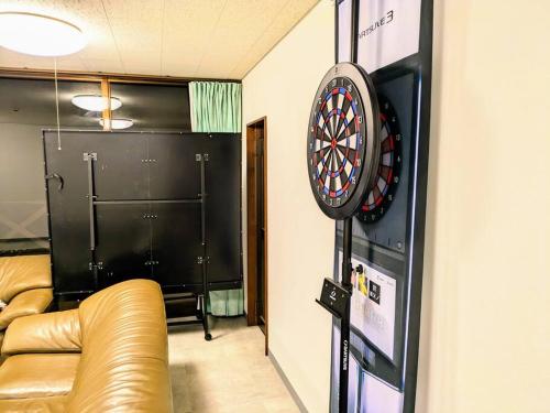 a room with a couch and a dart board on a wall at レインボーヒルズ 熱海 #ダーツ #卓球 #サウナ #バーベキュー in Atami