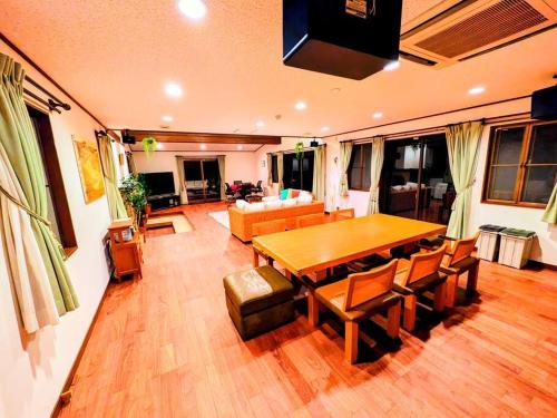 a living room with a wooden table and a couch at レインボーヒルズ 熱海 #ダーツ #卓球 #サウナ #バーベキュー in Atami