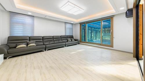 a living room with a couch and a large window at Daebudo Juni Pension in Ansan