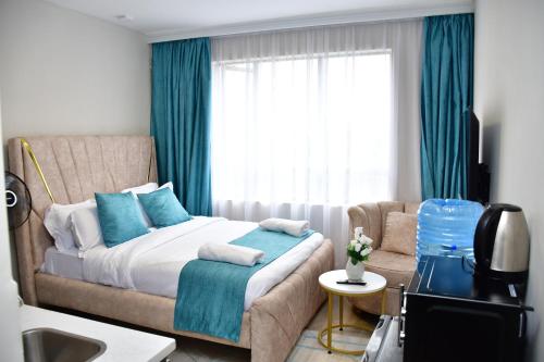 a bedroom with a bed and a couch and a window at Haydenco Suites Furnished Studios in Nairobi