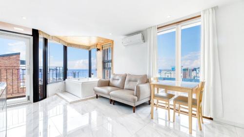 a living room with a chair and a desk and windows at Sokcho Moreve Pension in Sokcho