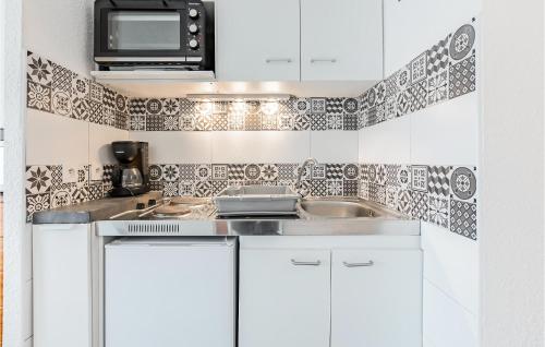 une cuisine blanche avec un évier et un micro-ondes dans l'établissement Gorgeous Apartment In Le Grau-Du-Roi, au Grau-du-Roi