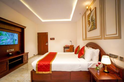 a hotel room with a bed and a flat screen tv at Hotel Yathin in Mysore