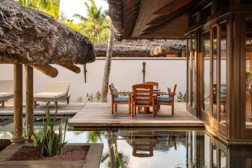 a patio with a table and chairs next to a pool at Constance Lemuria in Grand'Anse Praslin