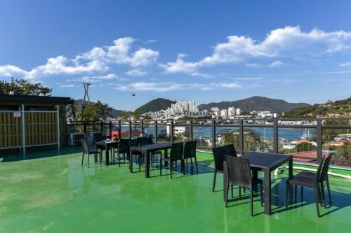un patio con tavoli e sedie su un tetto verde di Yeosu Chunghong Pension a Yeosu