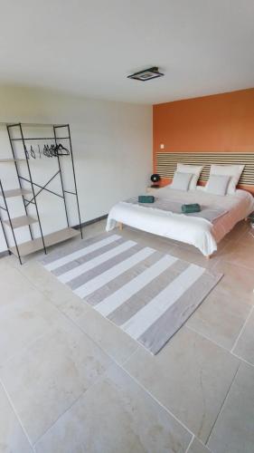 a bedroom with a large bed and an orange wall at Les Jardins Ducarouge 3 climatisé in Digoin