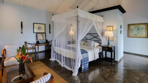 a bedroom with a canopy bed and a living room at Kahanda Kanda in Koggala