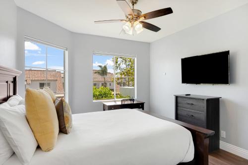 a white bedroom with a bed and a flat screen tv at Encantamar Escape by AvantStay Prime Location Community Amenities in Dana Point
