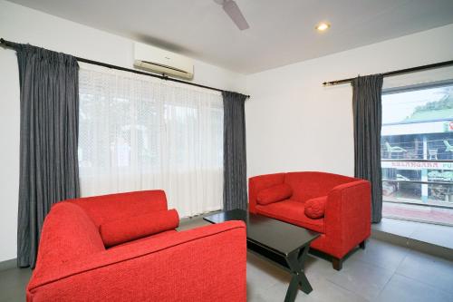 a living room with two red chairs and a window at Townhouse Mookkannoor Tourist Home in Cochin