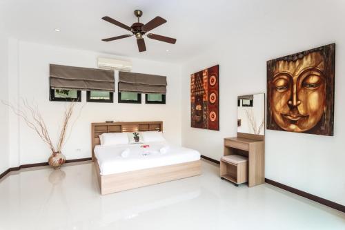 ein Schlafzimmer mit einem Bett und einem Deckenventilator in der Unterkunft Frangipani pool villa - garden, BBQ & maid in Nai Harn Beach