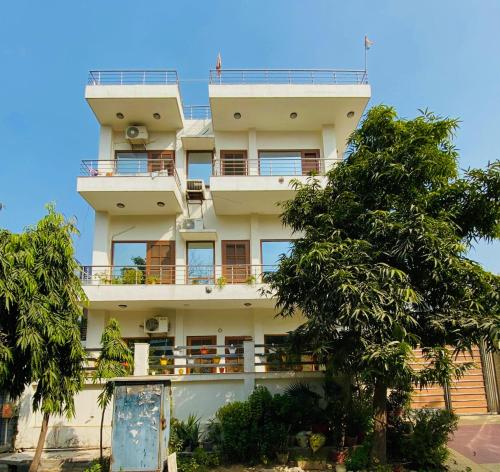 a tall white building with trees in front of it at House Of Vedas in Greater Noida