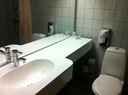 uma casa de banho com um lavatório, um WC e um espelho. em Hotel Nørherredhus em Nordborg