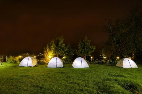 three tents sitting in a field at night at Cliff Club Resort Ooty in Ooty
