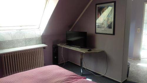 ein Schlafzimmer mit einem Schreibtisch und einem TV darauf in der Unterkunft Hotel am Schenkelberg in Saarbrücken