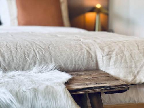 a bed with a white blanket and a wooden bench at Hidden Retreats 1466 Edition in Reichenbach