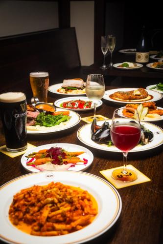 a table with plates of food and glasses of wine at Bat and Ball Hostel in Sydney