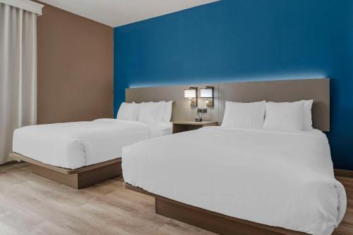 two beds in a hotel room with blue walls at Comfort Suites Hattiesburg near University in Hattiesburg