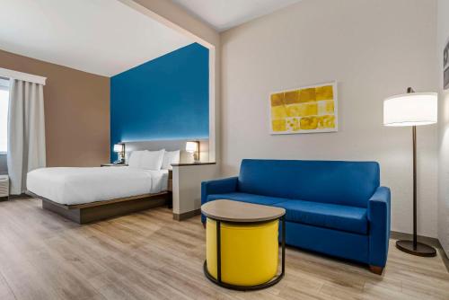 a hotel room with a bed and a blue couch at Comfort Suites Hattiesburg near University in Hattiesburg