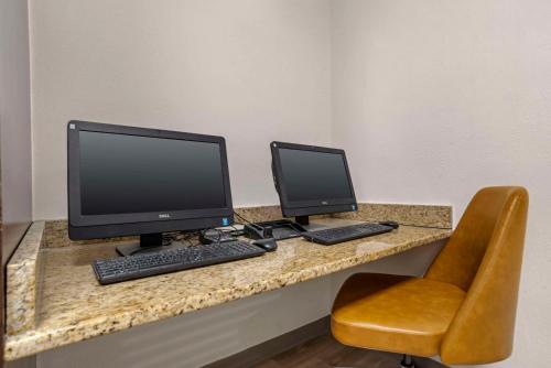 a desk with two computer monitors and a chair at Comfort Suites Hattiesburg near University in Hattiesburg