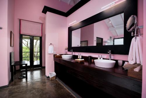 a bathroom with three sinks and a large mirror at Kahanda Kanda in Koggala