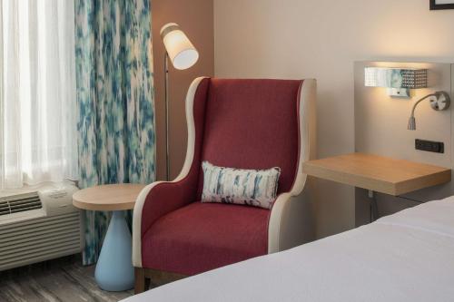 a hotel room with a red chair and a table at Hilton Garden Inn Tacoma Downtown in Tacoma