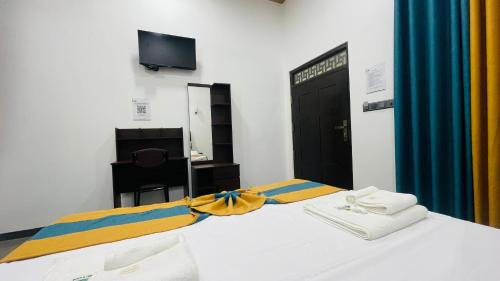 a bedroom with a bed with towels and a television at The Sanctum in Talaimannar