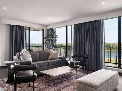 a living room with a couch and chairs and windows at Origin Kansas City Riverfront, a Wyndham Hotel in Kansas City