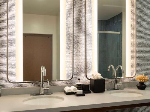 a bathroom with two sinks and two mirrors at Origin Kansas City Riverfront, a Wyndham Hotel in Kansas City