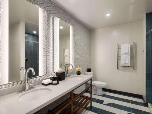 a bathroom with two sinks and a toilet at Origin Kansas City Riverfront, a Wyndham Hotel in Kansas City